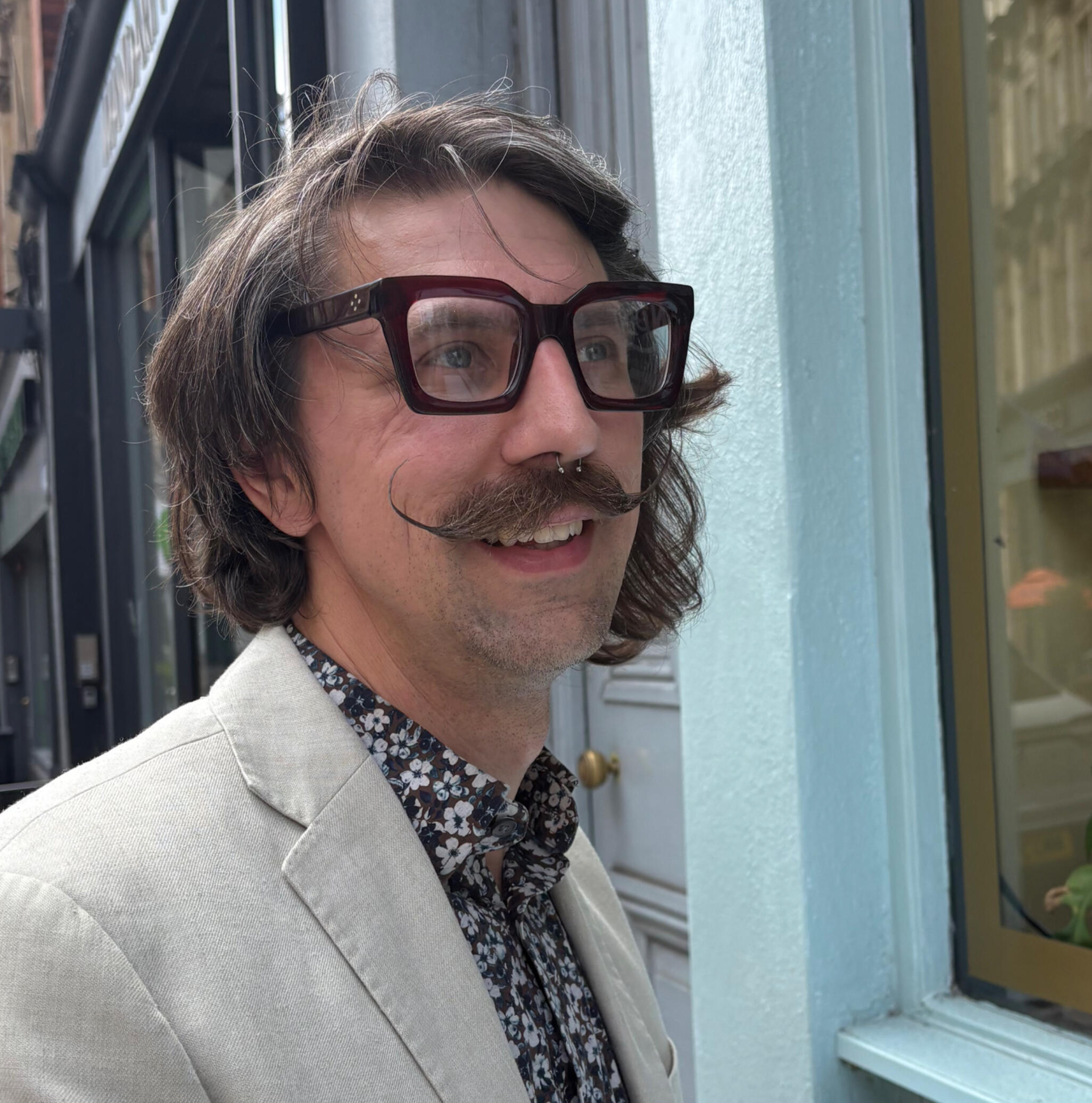 Joshua Gardner sat outside a cafe in Bristol in a cream linen suit having just drink a flat white his favourite coffee.